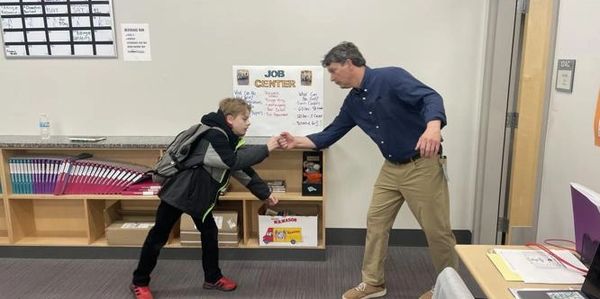 Teacher fist bumps a student in a classroom setting.