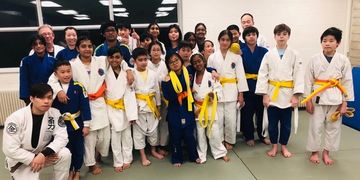 Group photo of kids and instructors in judo uniforms with colored belts.
