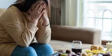 Woman sitting on a couch with her head in her hands, looking distressed.