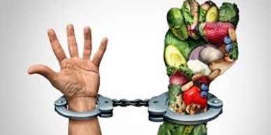 Hands in handcuffs, one natural and one made of vegetables, symbolizing healthy eating habits.