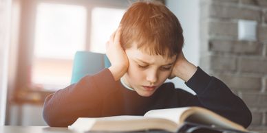 Young boy frustrated while reading a book.