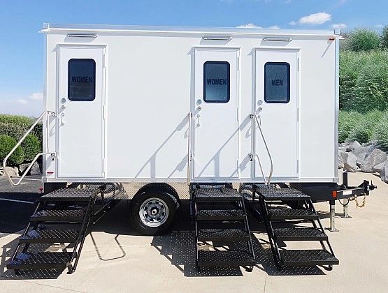 Portable restroom trailer with separate men and women doors.