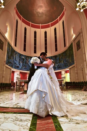 Newlyweds share a kiss inside a grand church during their wedding ceremony.