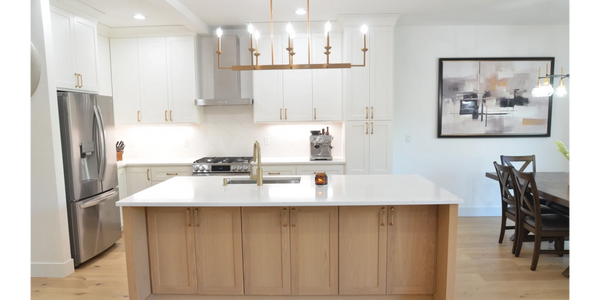 Kitchen with white cabinets, white oak island and gold hardware and faucet.  White oak floors