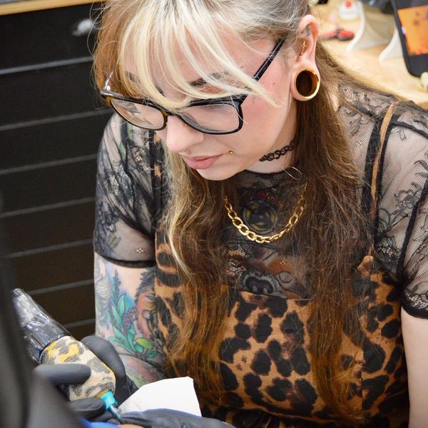 Tattoo artist focused on creating a detailed tattoo on a client's arm.