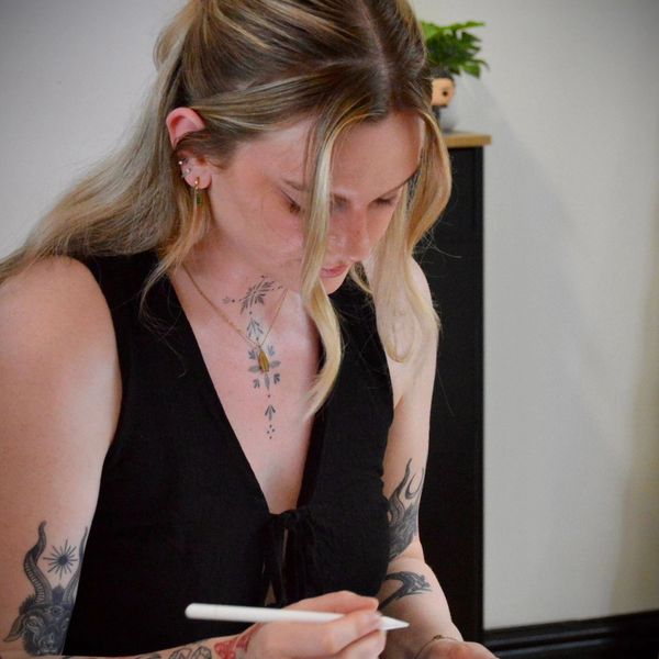 A tattooed woman drawing on a tablet with a stylus.