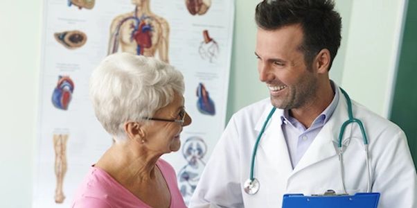 Smiling happy young doctor and elderly patient shaking hands.