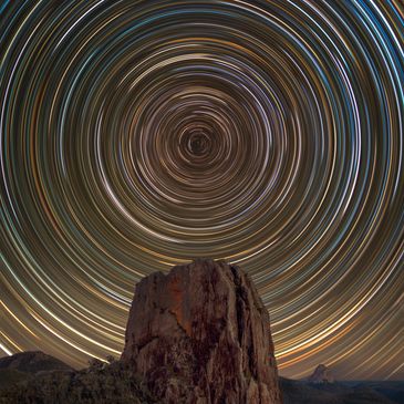 Circular star trails above a mountain peak.