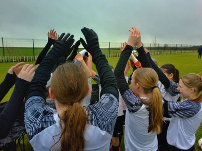 Team celebrating with raised hands on a sports field.