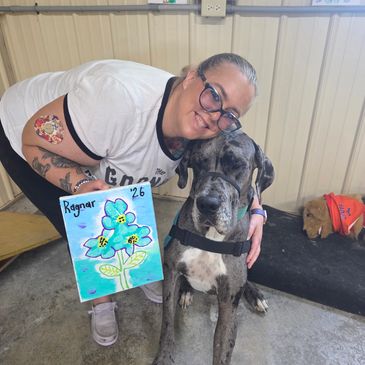 Woman hugging a large Great Dane with a drawing.