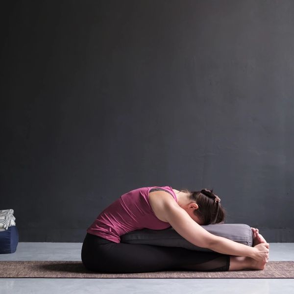 Yin Joga, joga powięziowa, kobieta ćwiczy yin jogę z wałkiem
