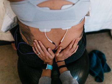 TENS Unit on a mother's back to help with pain management in childbirth. Birth doula supporting her.