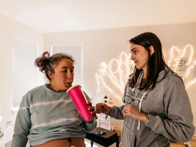 Birth doula giving water to a laboring mother at a home birth.