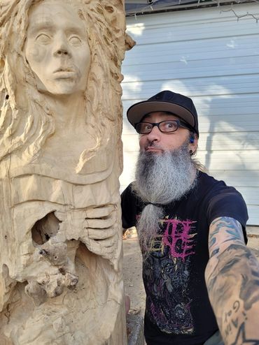 Artist Chad Rev standing next to a large scarlet oak work in progress