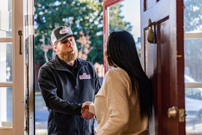 Delivery man shaking hands with a woman at the door.