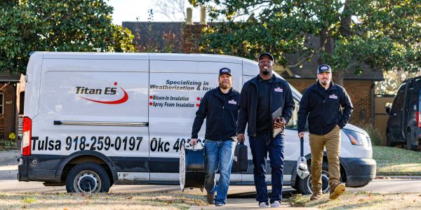 Three insulation workers walking in front of a company van.