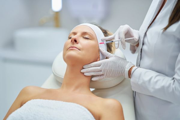 A patient lies on a treatment table while a healthcare professional administers an injection
