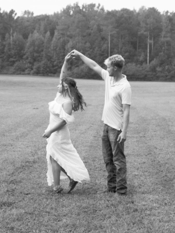 Couple dancing outdoors in a grassy field.