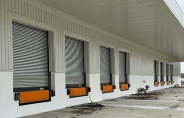 Row of closed industrial loading dock doors on a warehouse building.