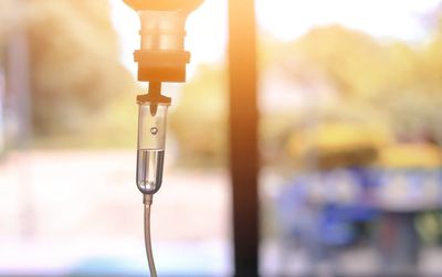 Close-up of a medical IV drip with bright sunlight in the background.