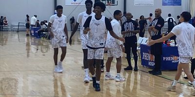 Young basketball players in white jerseys on a gym court.