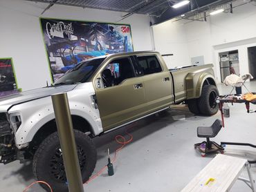 A partially painted pickup truck inside a garage or workshop.