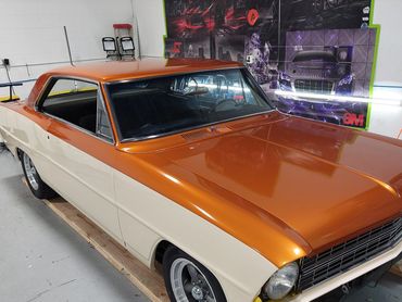 A classic two-tone orange and cream car in a workshop.