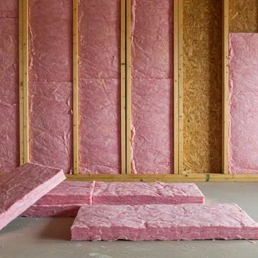 Image of fiberglass insulation being installed into a wall.