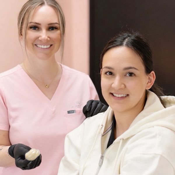 Smiling dental professional with patient, holding dental impression material.