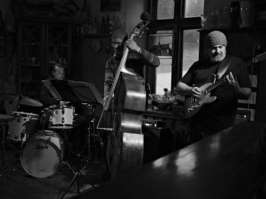Black and white photo of a jazz trio playing in a cozy room.