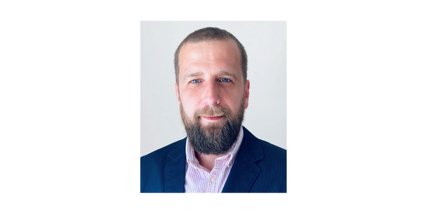 Professional man with beard wearing a suit jacket and striped shirt.