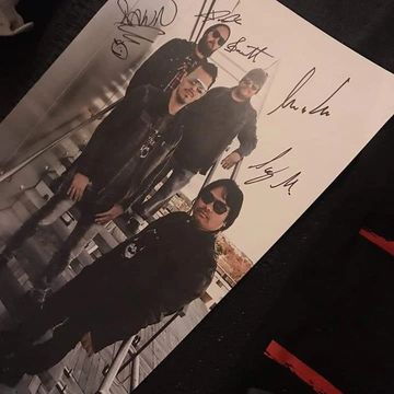 Signed Poster of band members standing on stairs with city in background