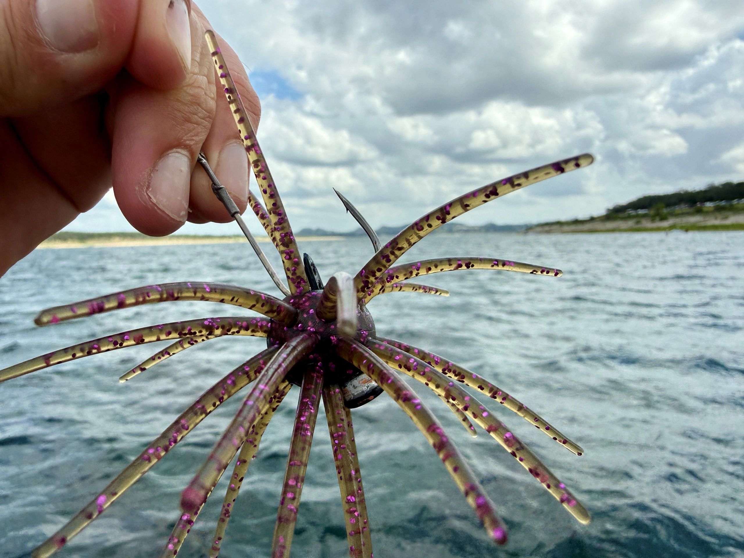 Hand holding a fishing lure with hooks.