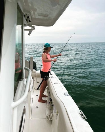 A young woman fishing on a boat in calm sea waters.