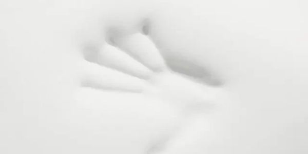 Hand pressing against a soft, white surface creating an imprint.