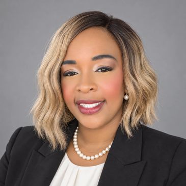 Professional woman with blonde wavy hair and pearl necklace.