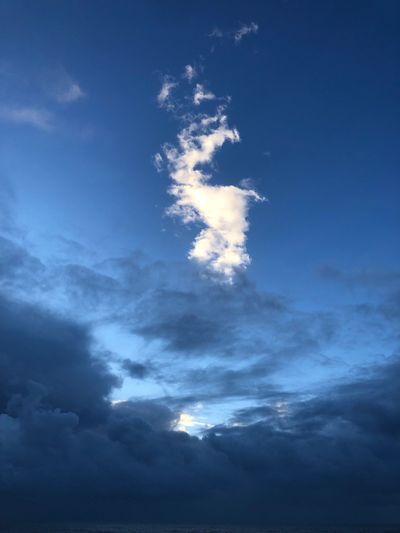 Dark storm clouds with blue sky and a bright white cloud above