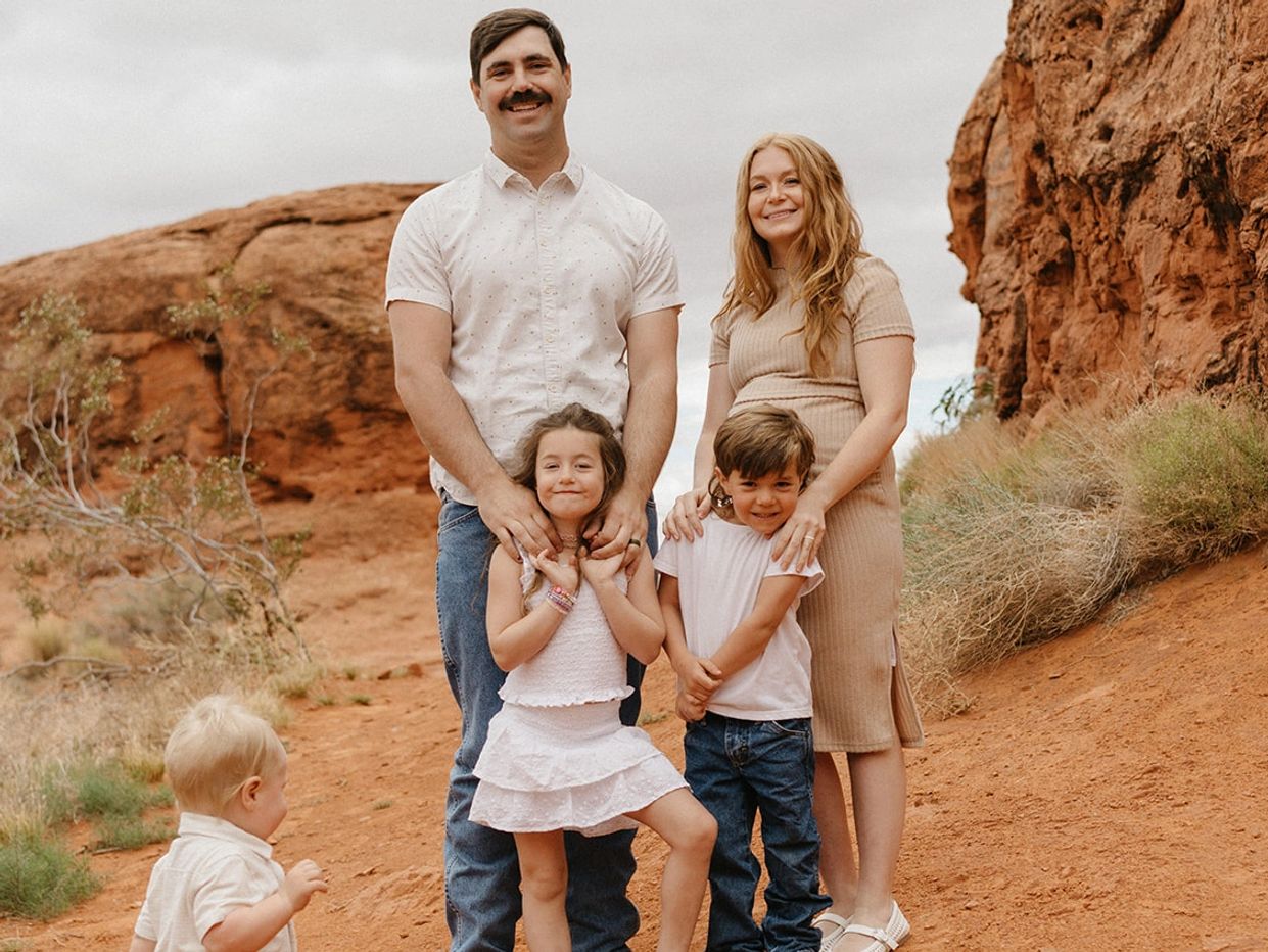 A family of five posing together in a rocky desert landscape.