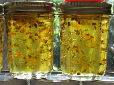 Two jars of homemade jelly with suspended fruit pieces.
