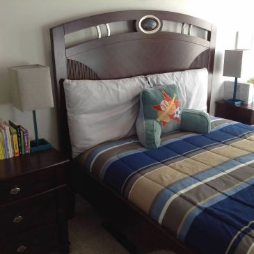 Neatly made bed with striped comforter and decorative pillow.