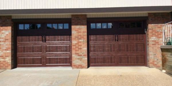 Two wooden garage doors on a brick building.