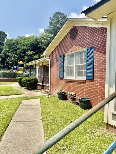 Brick house with blue shutters and a playground in the background.