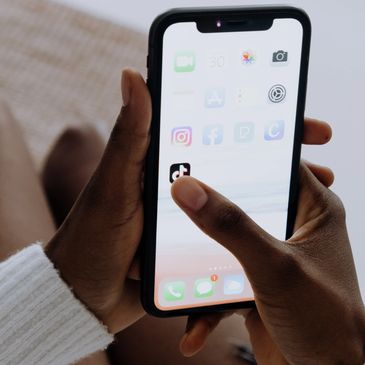 Person holding an iPhone and clicking on TikTok social media app