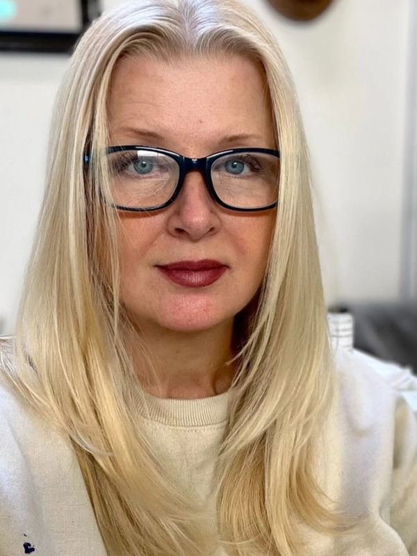 Blonde woman with glasses, wearing a light-colored sweater, looking directly at the camera.