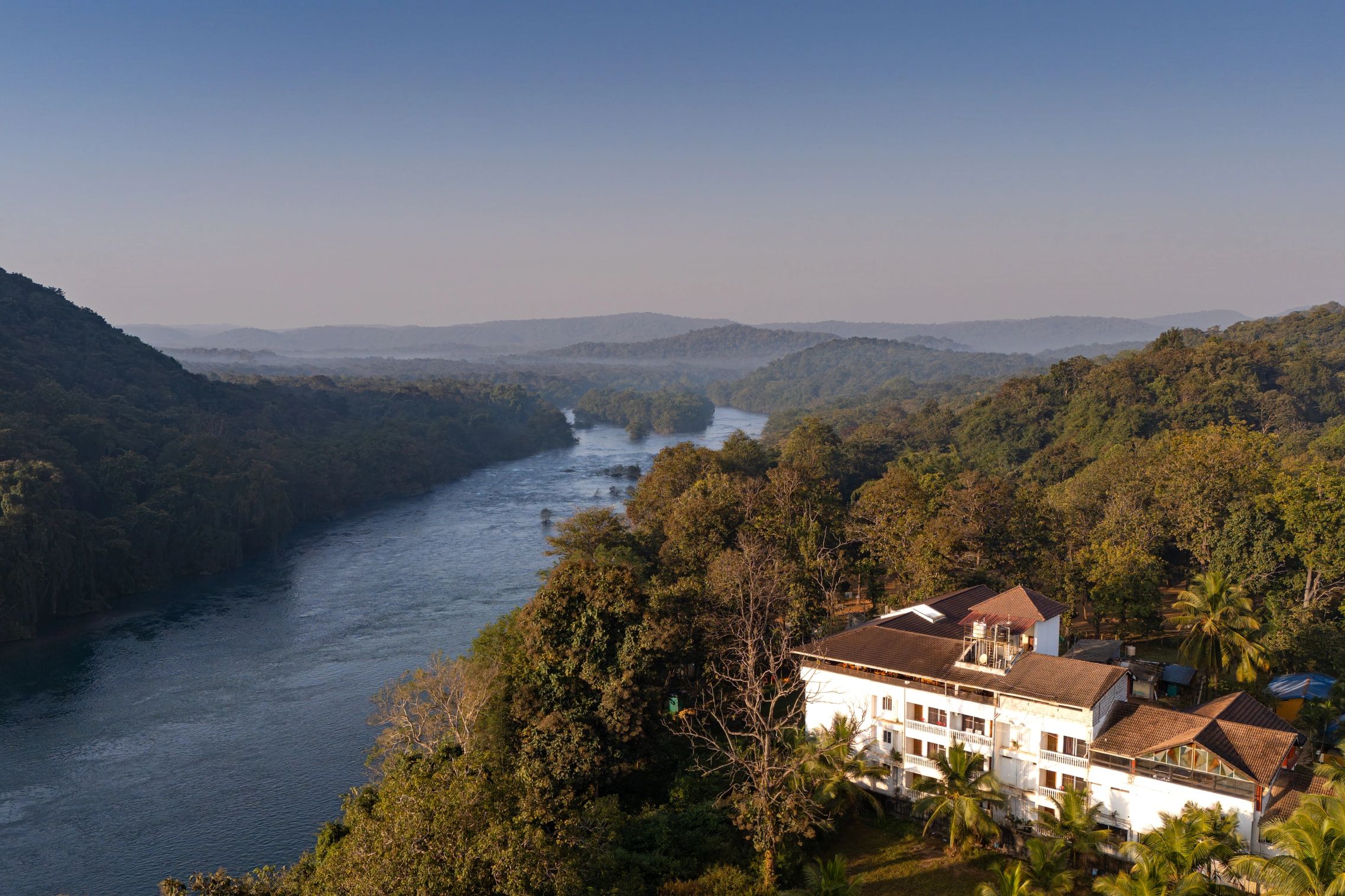 River flowing through lush forested hills with a building in the foreground.
