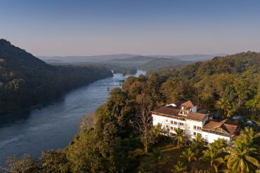 River flowing through lush forested hills with a building in the foreground.
