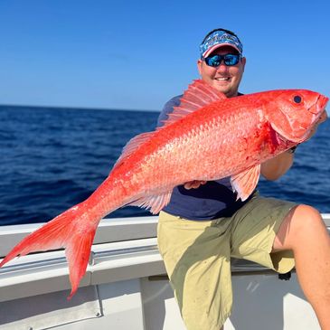 Captain Chris holding his personal best queen snapper from a deep drop trip