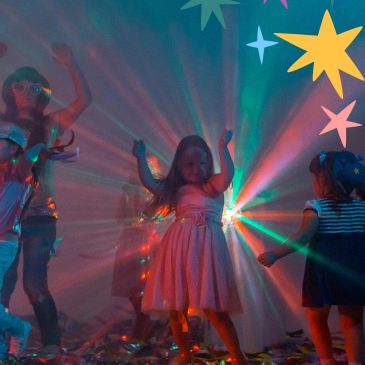 Children dancing joyfully under colorful party lights.