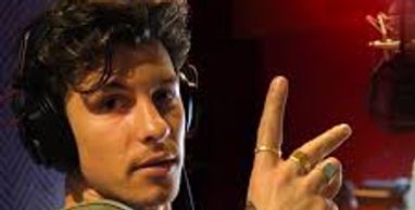 Man wearing headphones showing peace sign in a recording studio.