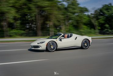 White Ferrari 296 GTS with the top down on the highway